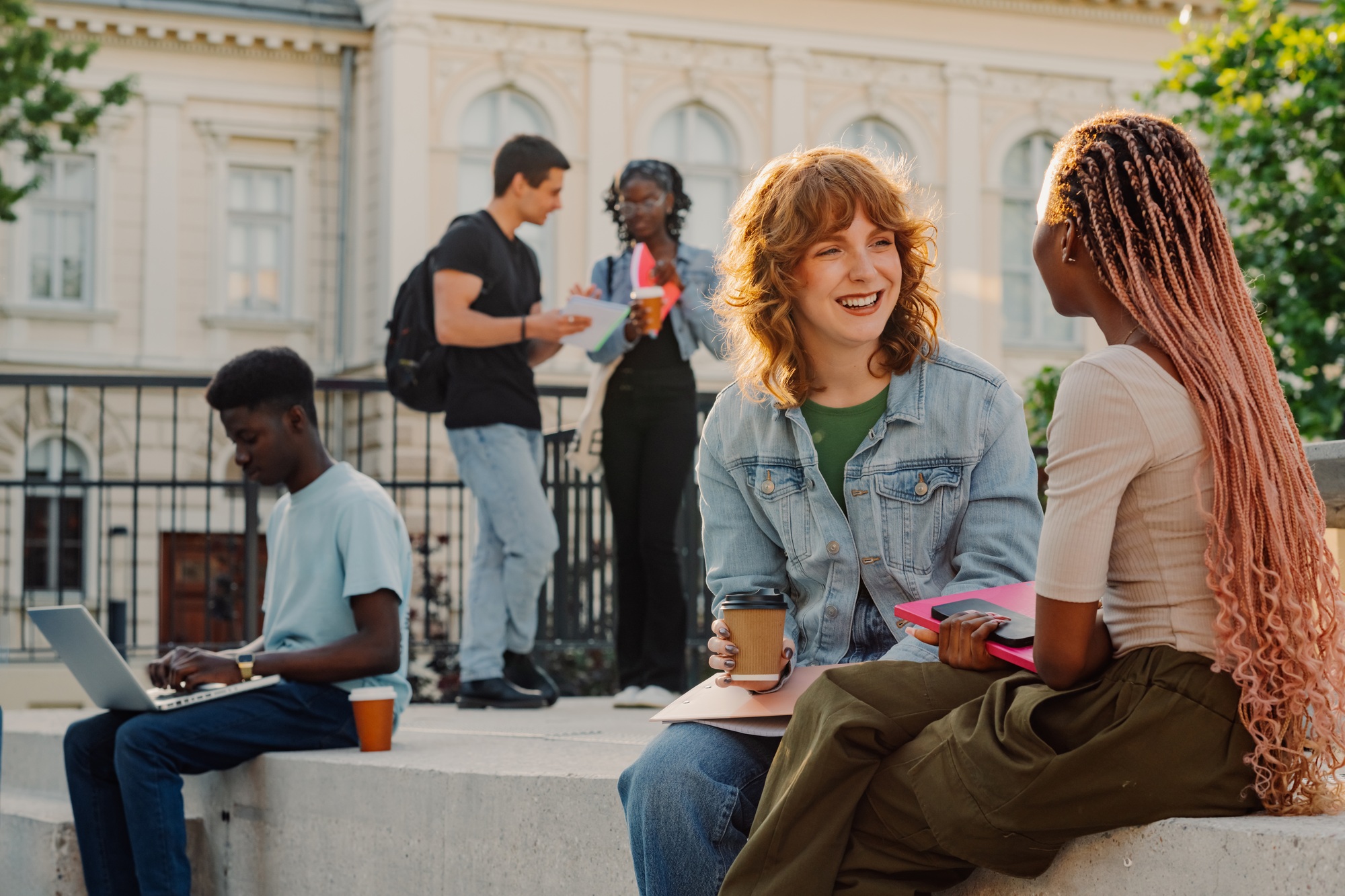 Portrait of female diverse students on stairs at university campus chatting