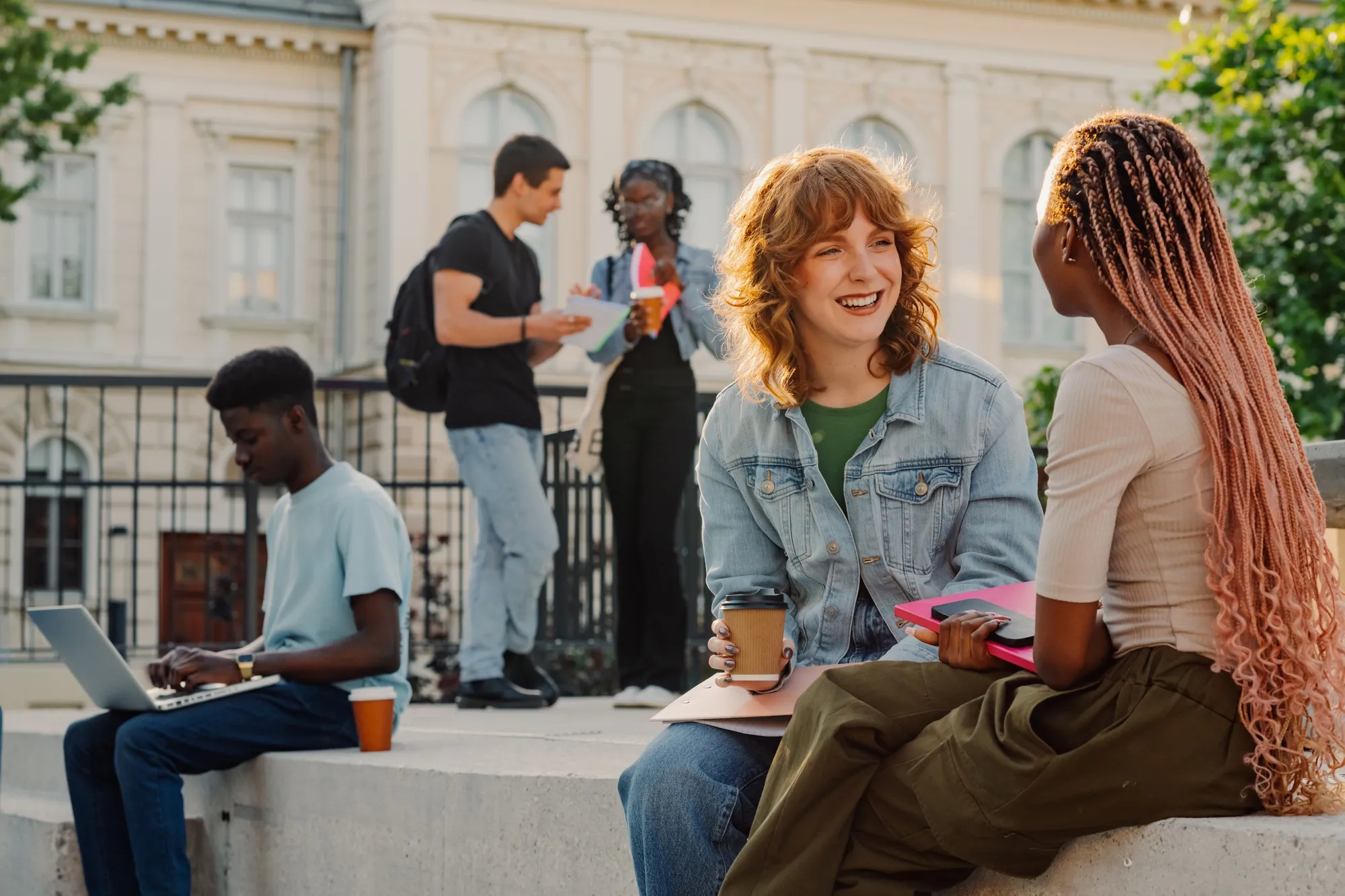 Portrait of female diverse students on stairs at university campus chatting